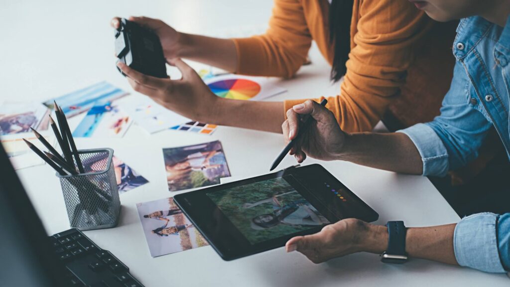 Two people sit at a white desk and work on an iPad, demonstrating brand creative strategies for growth.