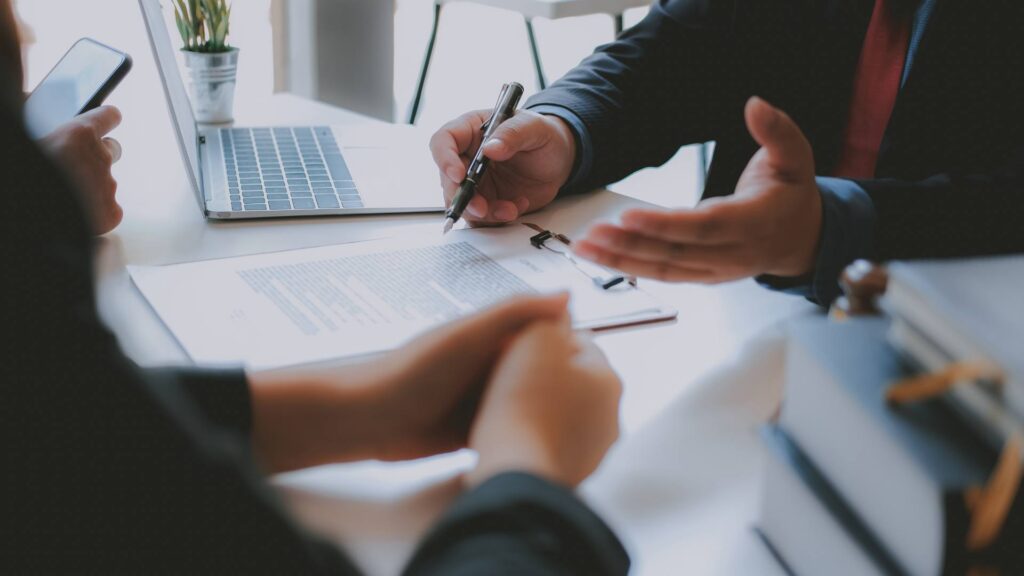 Two people sit at a white desk and talk, demonstrating brand consulting.