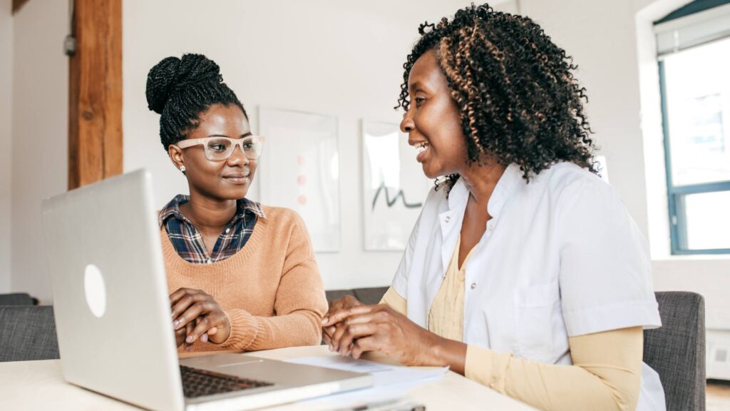 Two people sit at a desk, demonstrating the process of having an entrepreneur consultant.