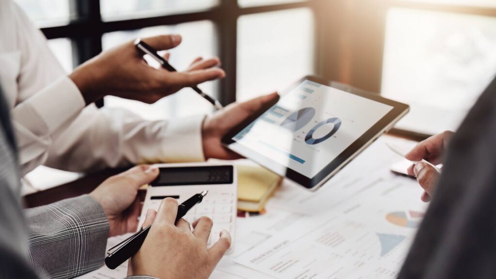 Hands are displayed holds pens, a calculator, and an iPad, demonstrating market research.